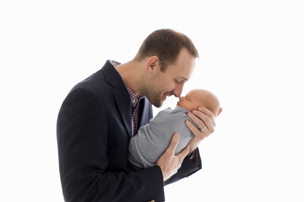 Intimate family moment against white background in business attire.