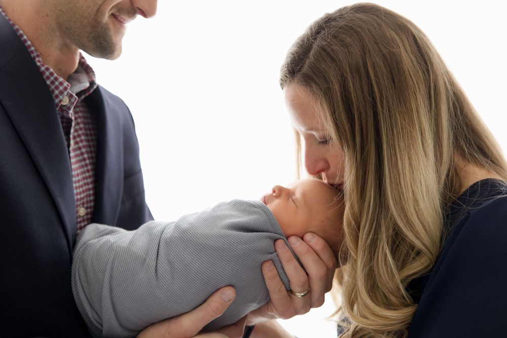 Intimate family portrait against white background showing tender moment.