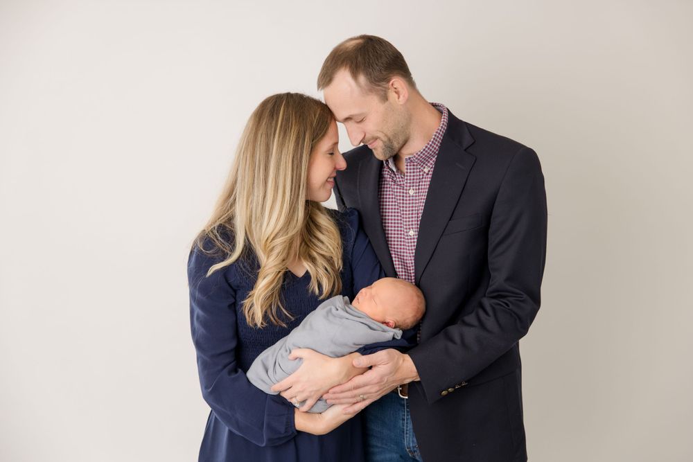 Intimate family moment captured against neutral backdrop in coordinated formal wear.