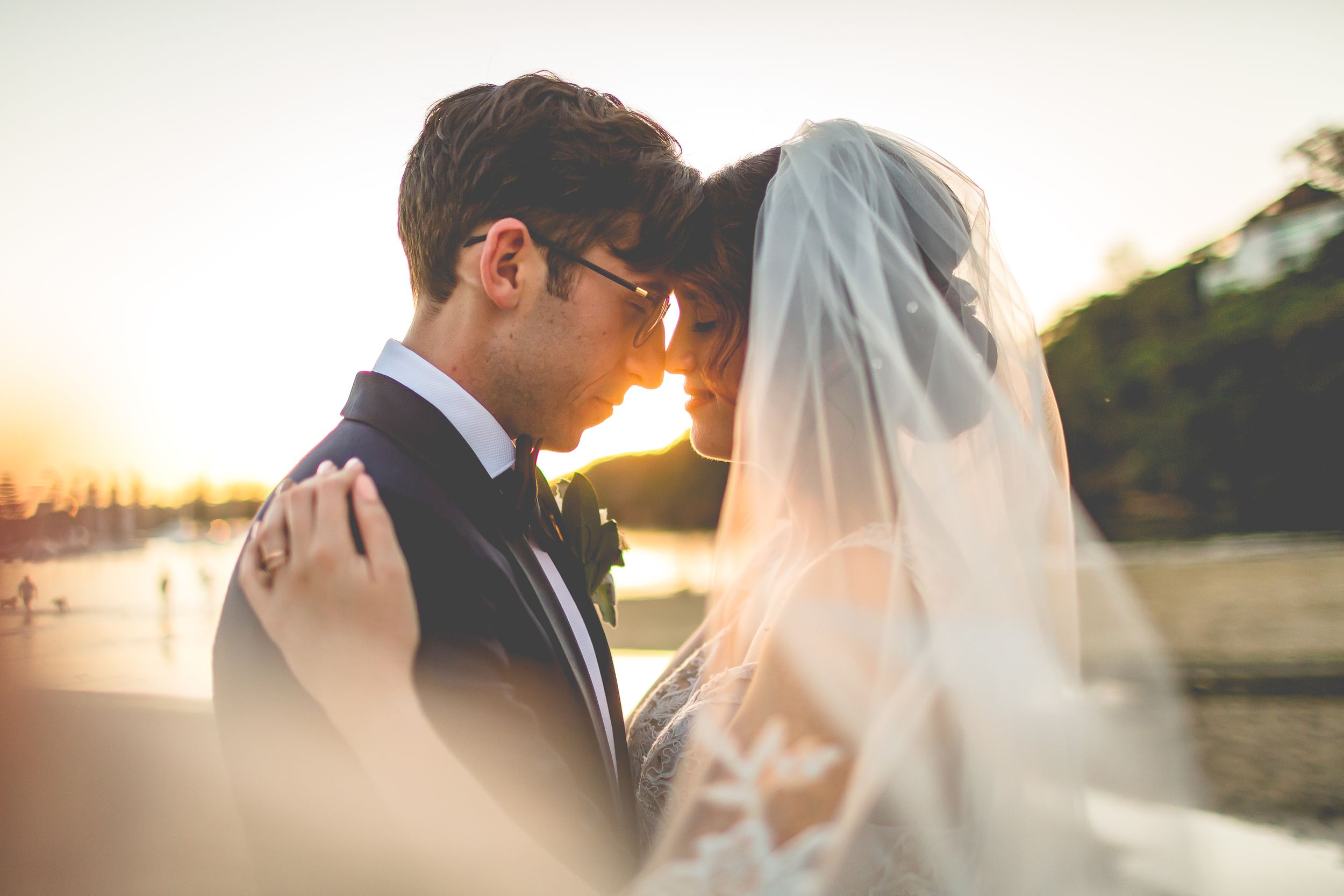Romantic sunset wedding portrait with soft golden light filtering through veil.