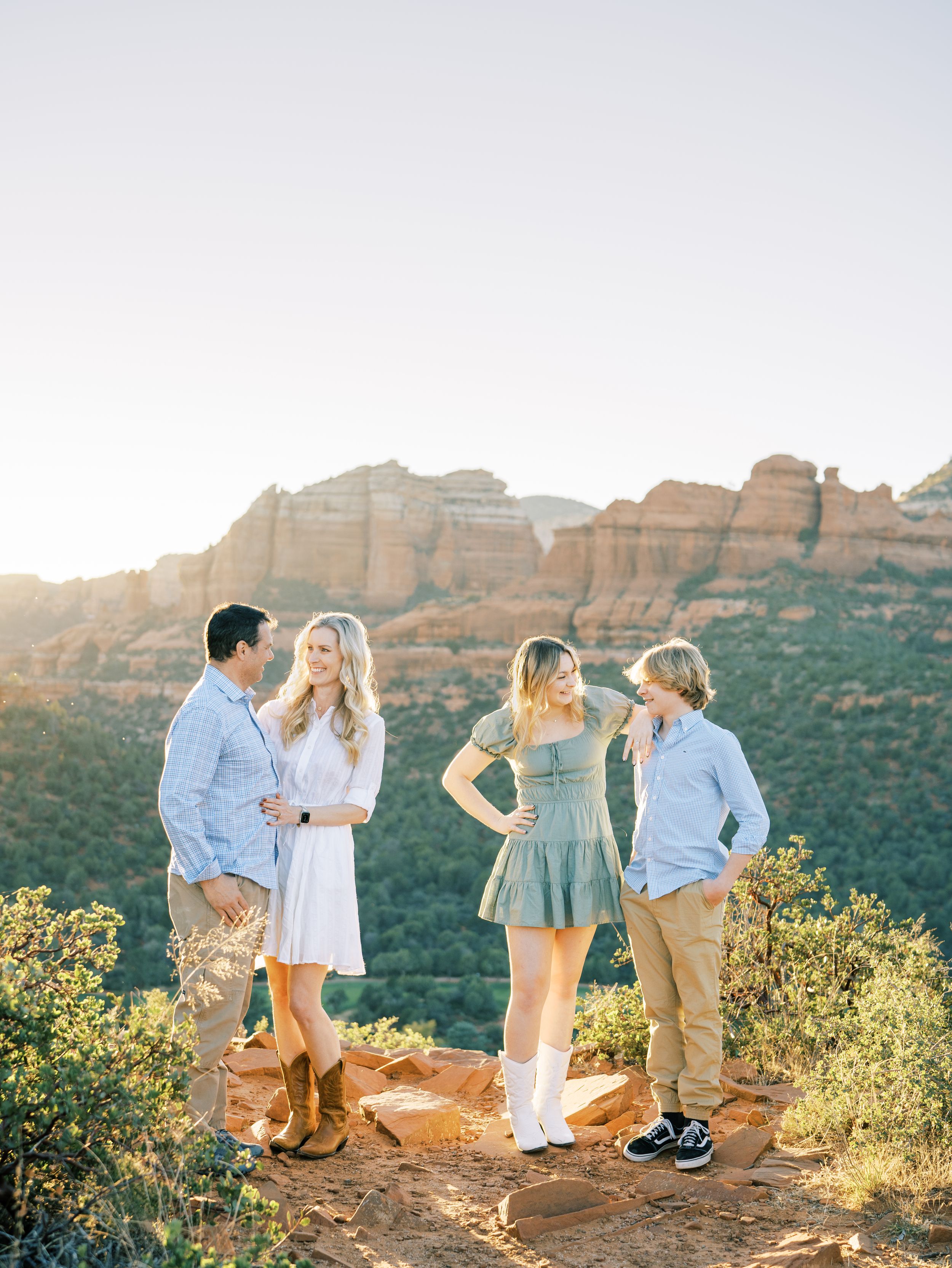 Two couples chatting on a red rock overlook with mountains in the background.