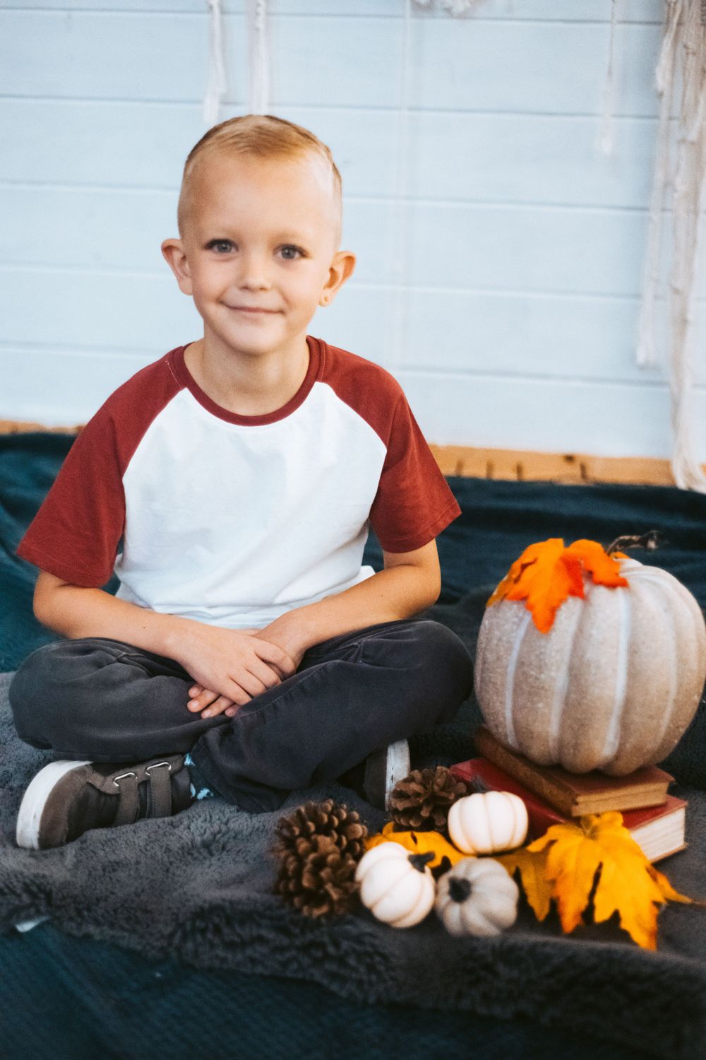 Fall themed portrait with pumpkins, pinecones and autumn decorations.