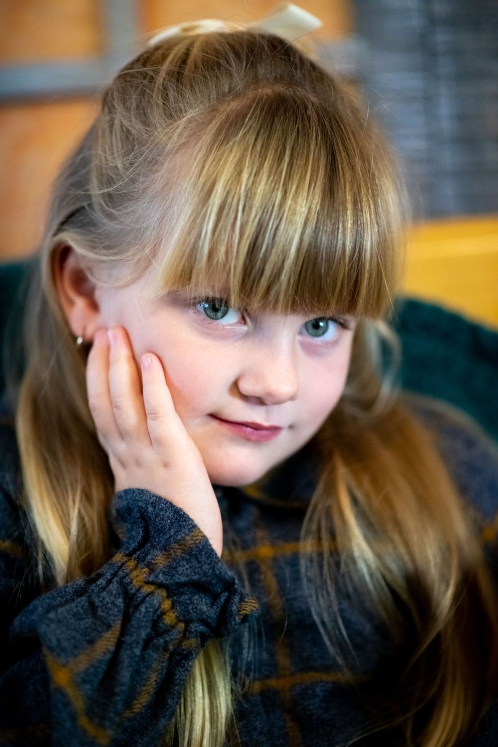 Portrait with blonde hair and bangs resting head on hand.