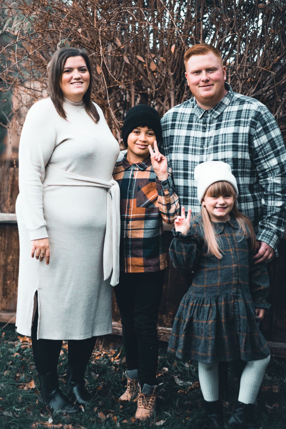 Family of four in coordinated outfits standing together outdoors.