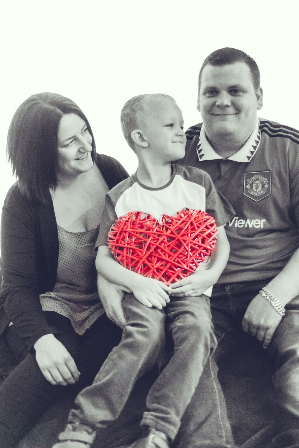 Black and white portrait with red woven heart prop and Manchester United jersey.