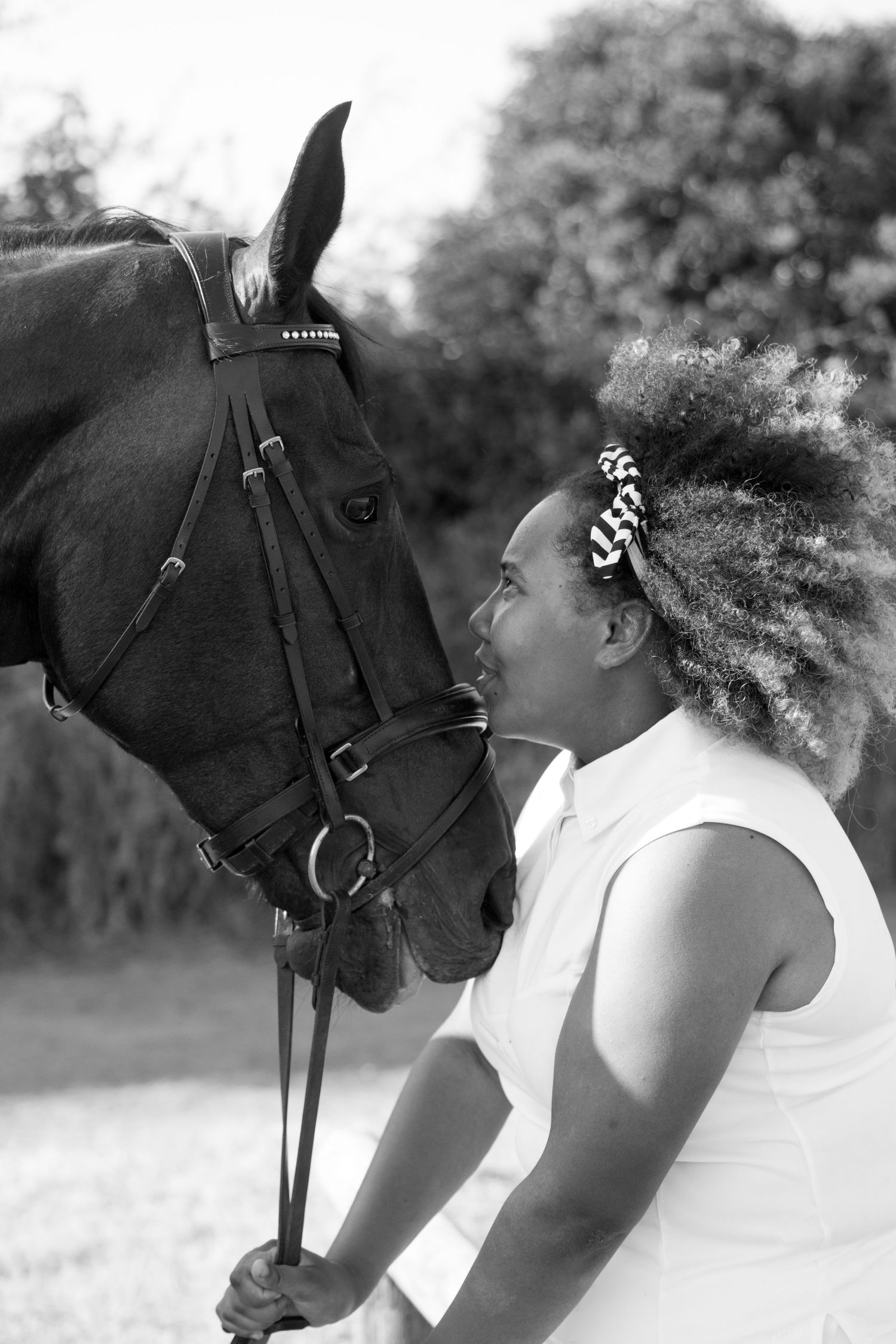 A heartwarming black and white photo of someone sharing an intimate moment with a beautiful black horse.