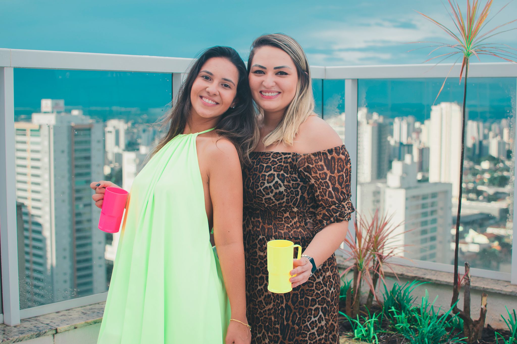 Friends enjoying a rooftop gathering with city skyline views in bright summer outfits.