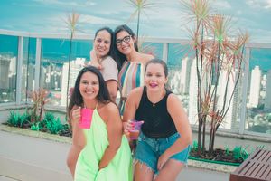 Friends socializing at a rooftop party with urban skyline backdrop on a bright day.