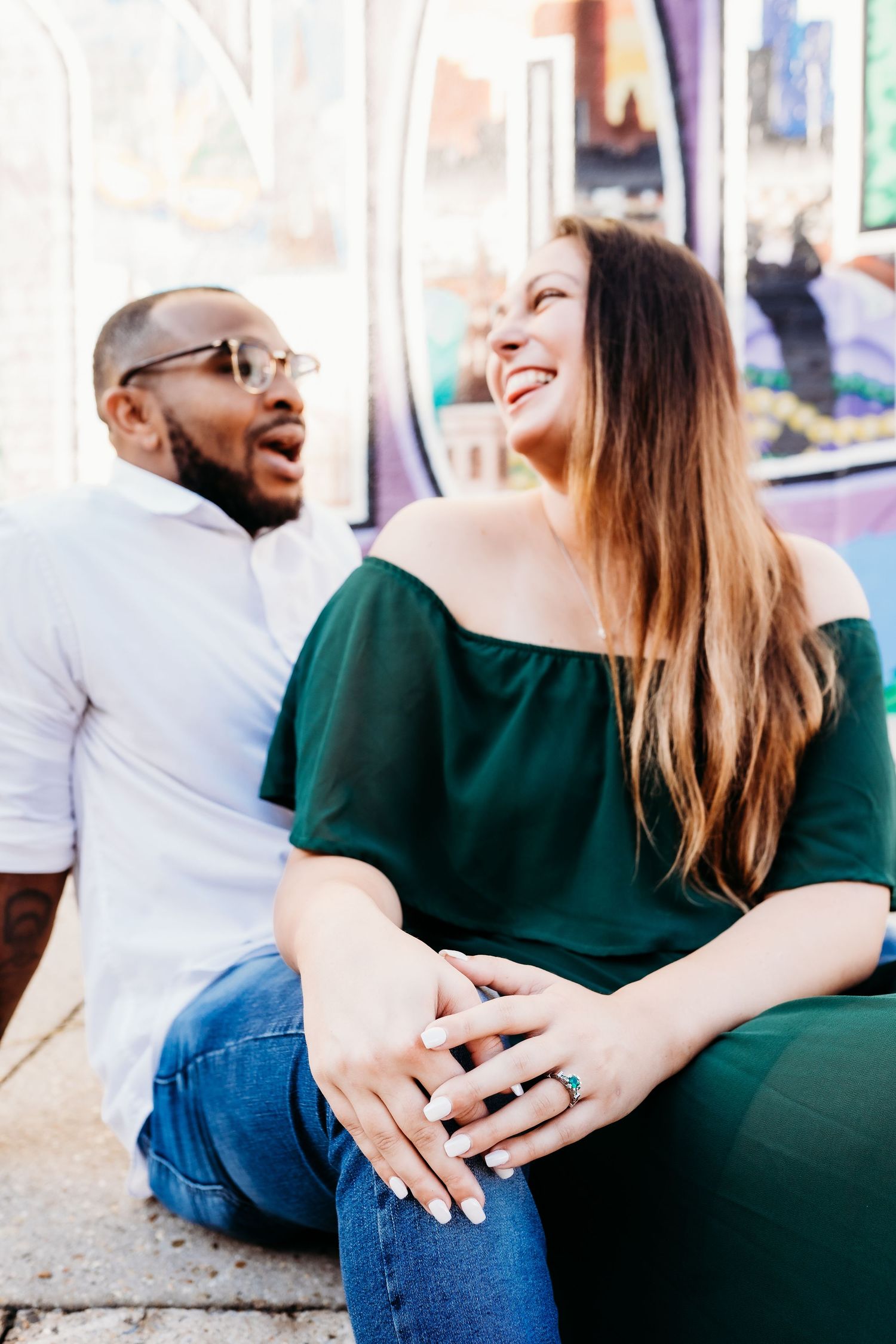 Candid engagement photo of couple laughing together outdoors.