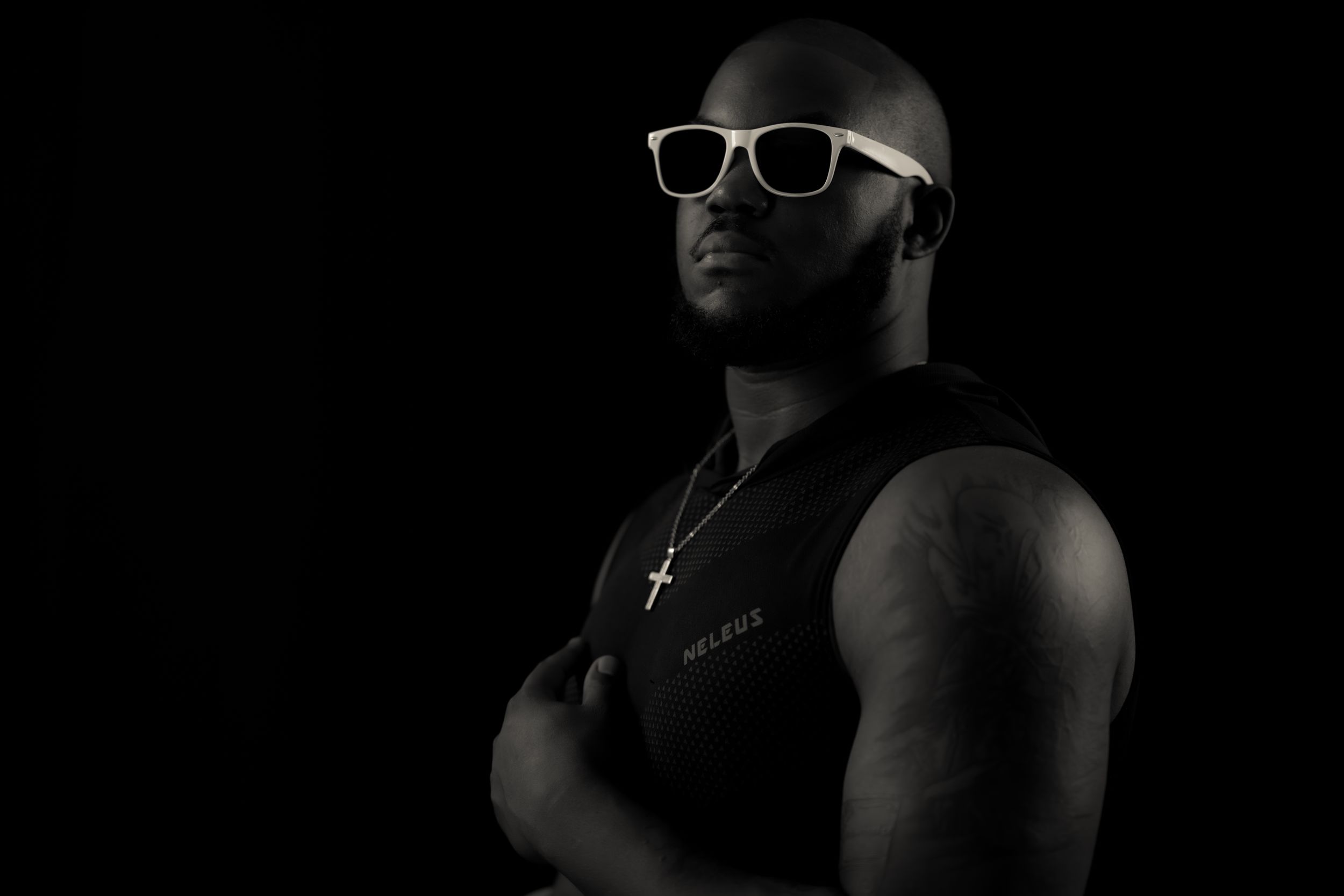 Noir-style portrait highlighting white sunglasses in dramatic shadows.