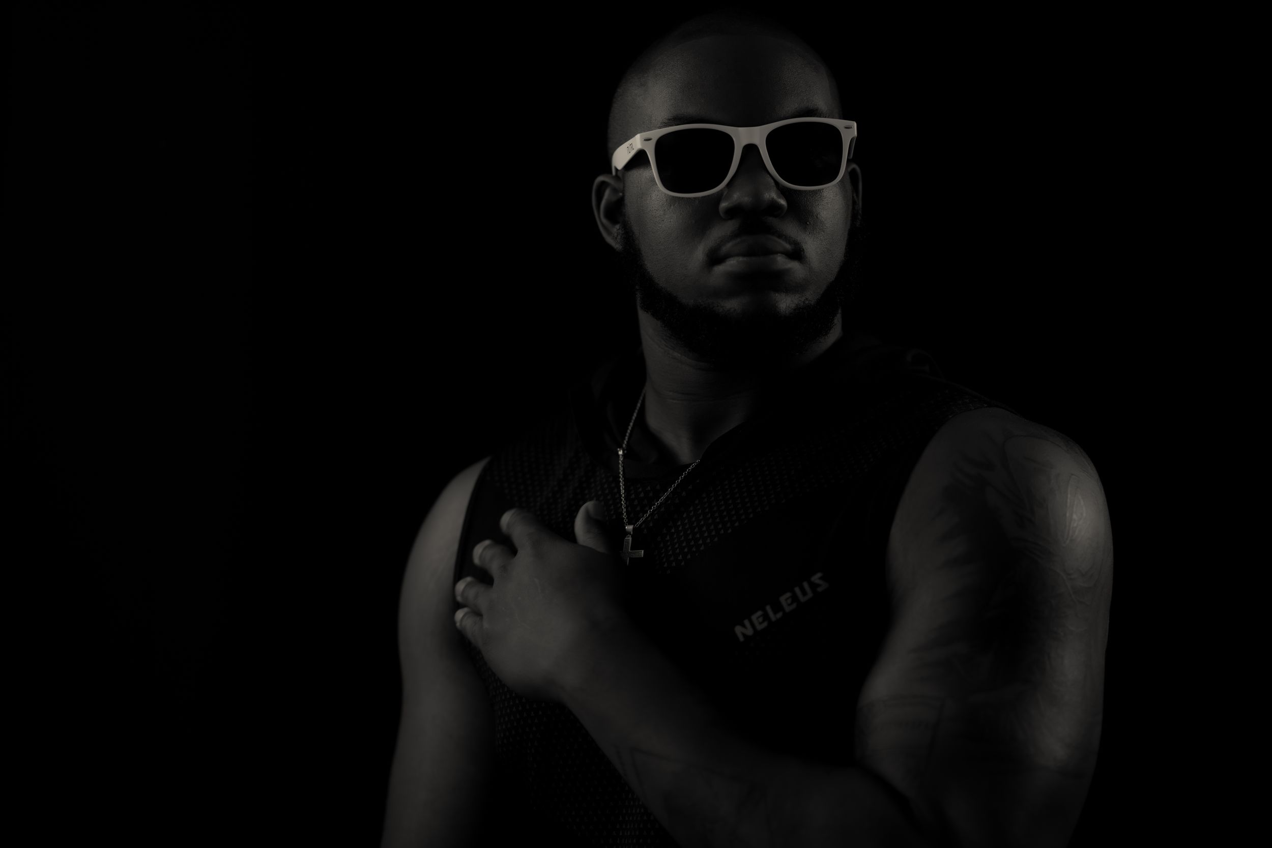 Monochromatic photo of person wearing white sunglasses with dramatic lighting.