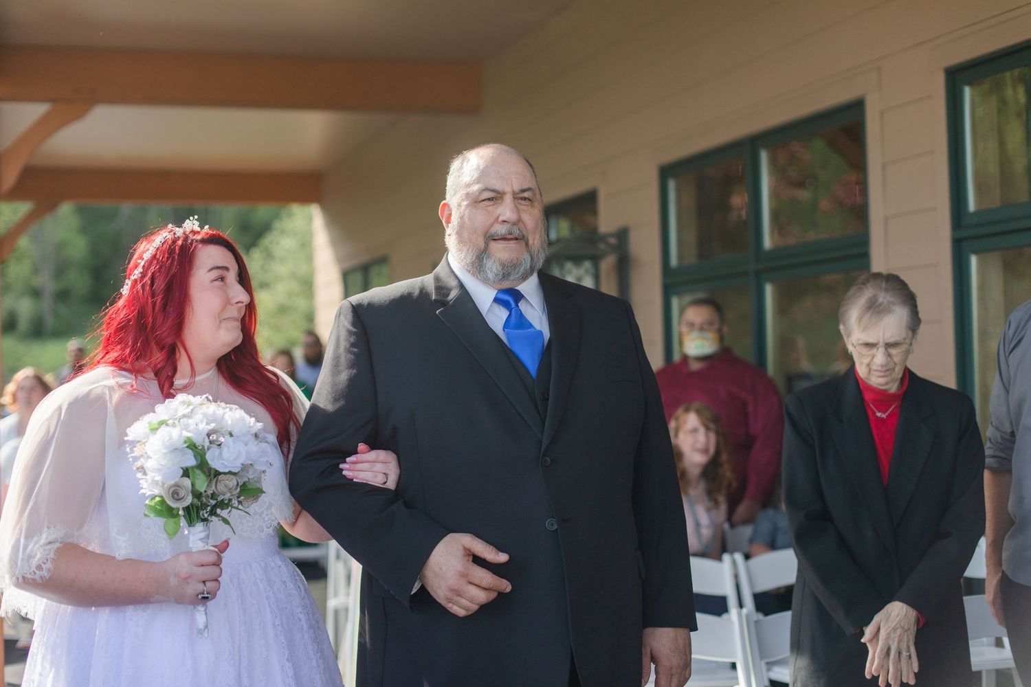 Wedding ceremony participants gathered under a covered outdoor venue with mountain views.