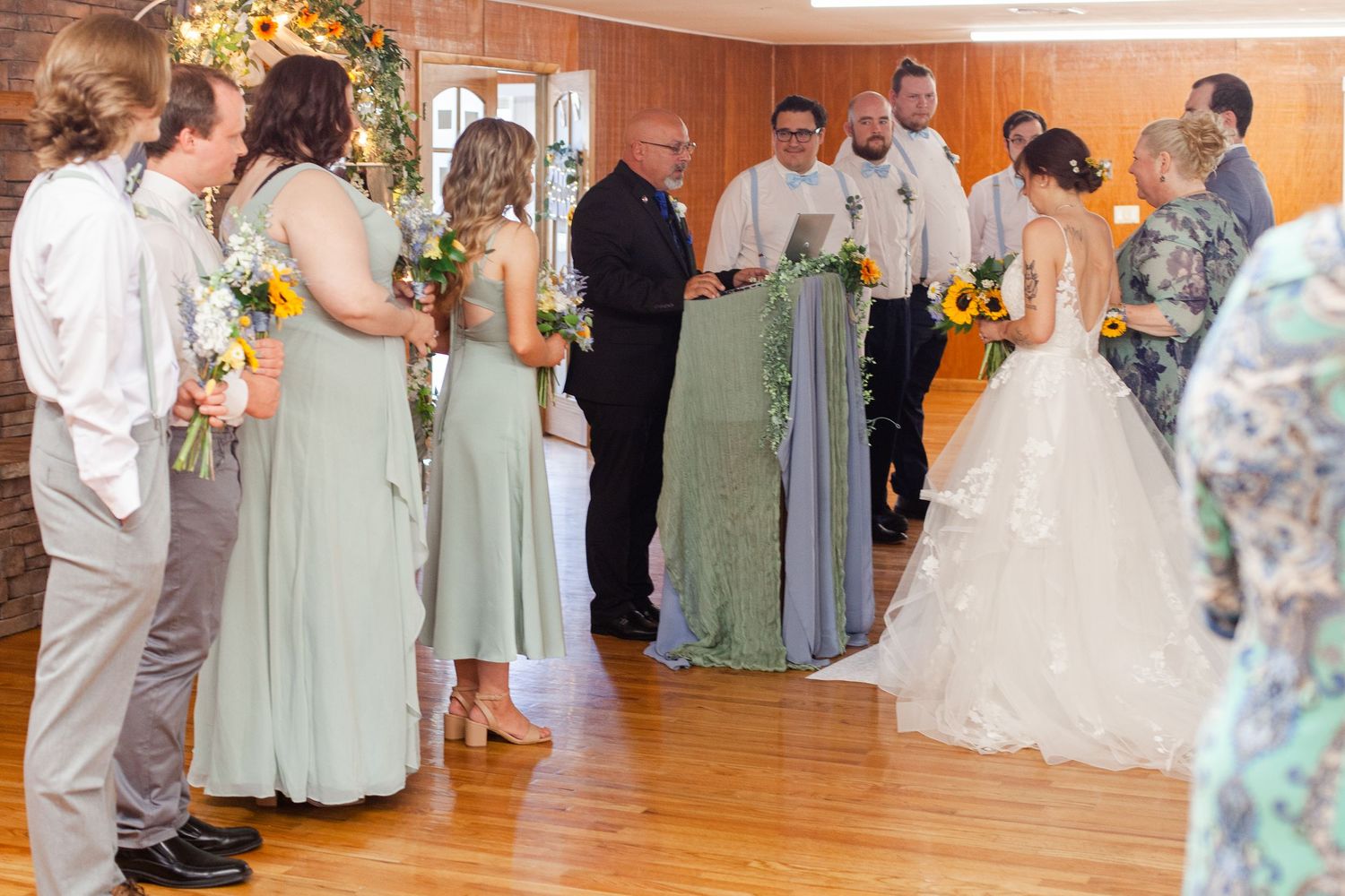 Wedding reception showing bridal party in sage green dresses and formal attire.
