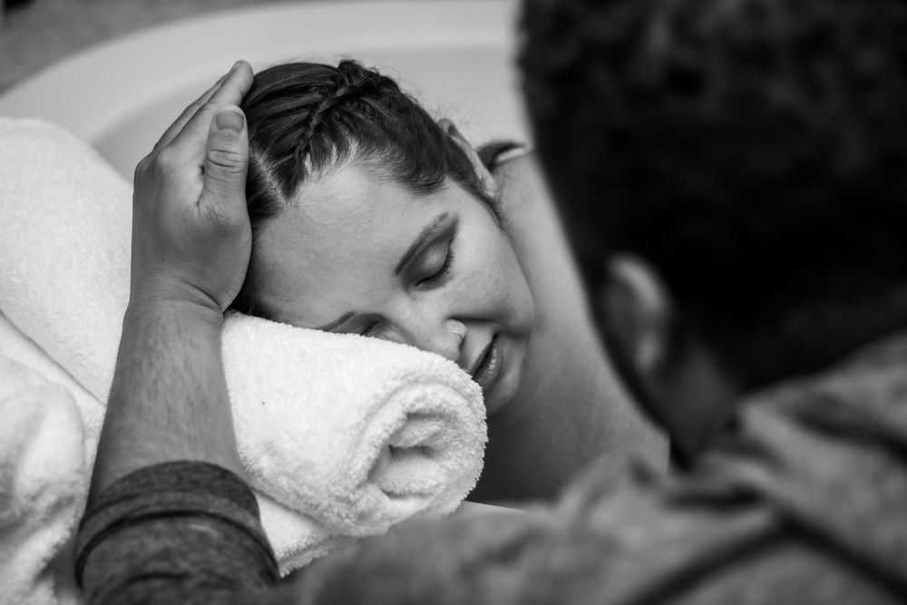Black and white photo capturing first moments with newborn baby in hospital.