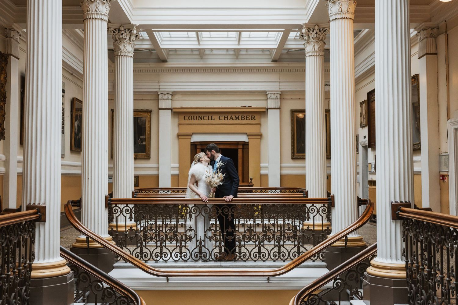 newly wed couple kissing in the Brighton Town Hall under the sky light