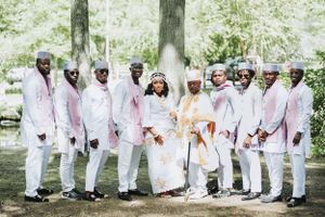 A wedding party poses outdoors wearing coordinated white and pink formal attire.