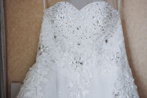 Close-up detail of a white wedding dress bodice with intricate beading and lace embellishments.