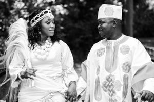 An artistic black and white photo of newlyweds in traditional African wedding attire.