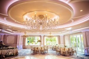 Elegant ballroom with crystal chandelier and round tables set for a wedding reception.