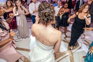Back view of a bride in a strapless gown dancing surrounded by wedding guests.