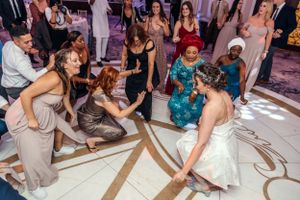 Wedding guests dancing and celebrating on an ornately decorated ballroom floor.