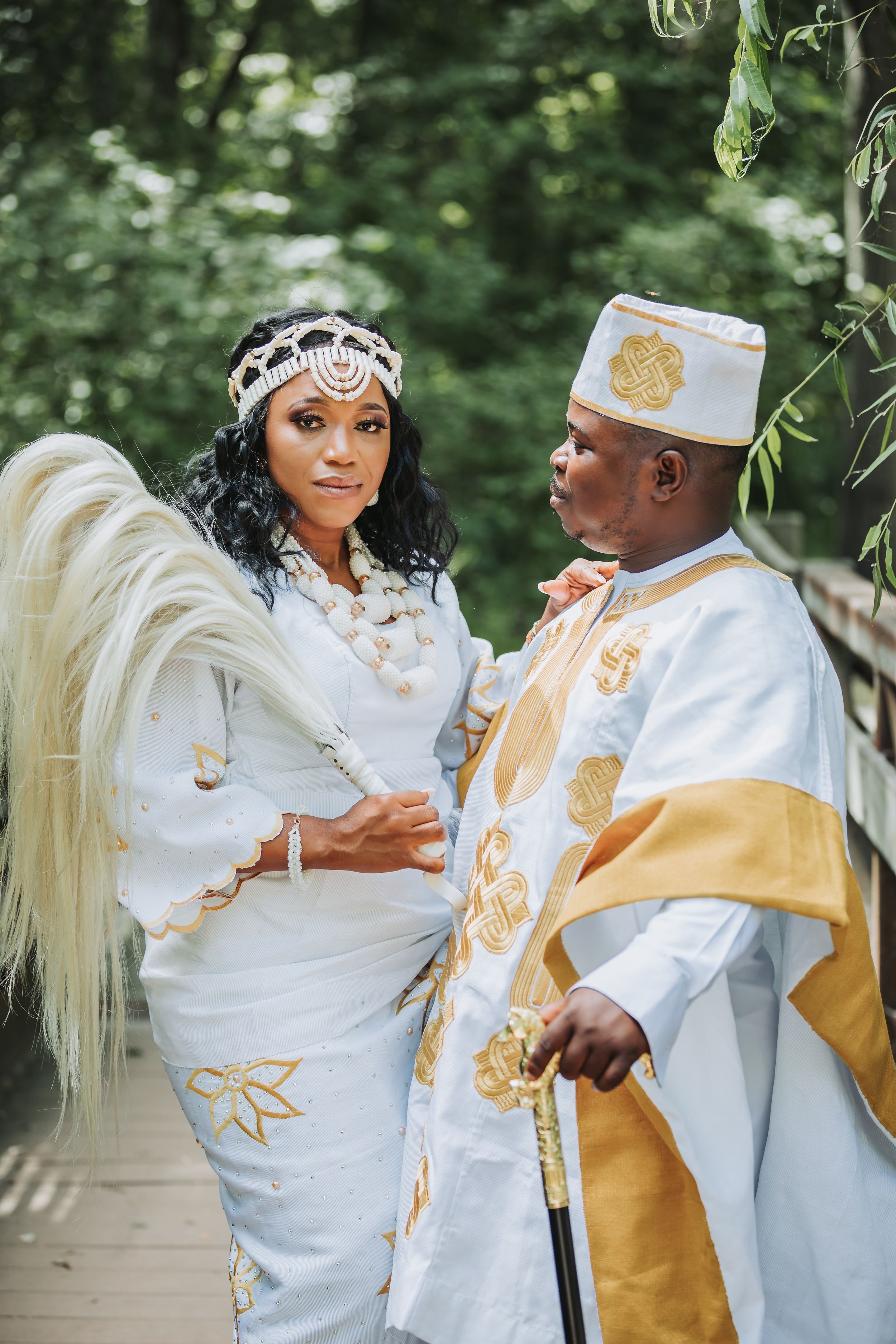 A traditional African wedding ceremony with the couple wearing ornate white and gold cultural attire.