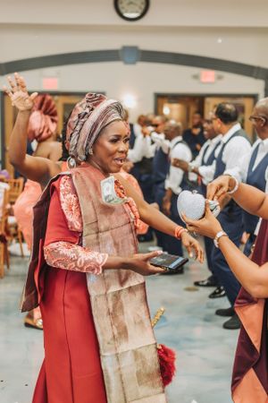 A guest in traditional African attire dances and celebrates during a wedding reception.