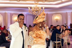 Emotional reception moment in an elegant ballroom with chandelier and peach decor.