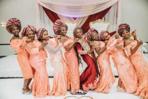 Bridesmaids in coral dresses strike playful poses during wedding photo session.