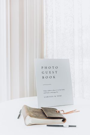 Minimalist white photo guest book displayed with pen on white surface.