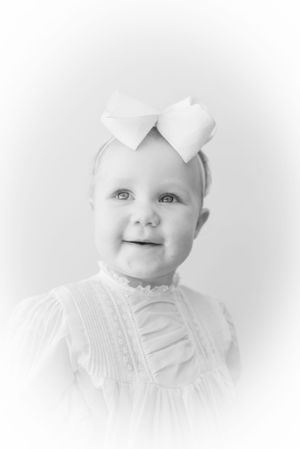 Black and white close-up portraits of a baby in white clothing showing different expressions.