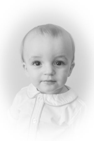 Black and white close-up portraits of baby wearing white collar.