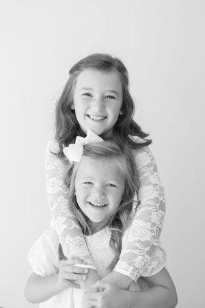 Black and white photos of children in white lace dresses playing together.