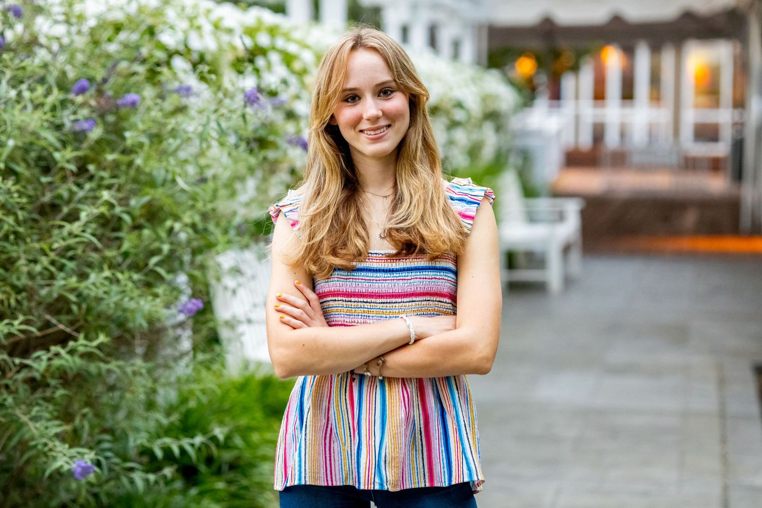 Person standing in front of a garden wearing a colorful striped top.