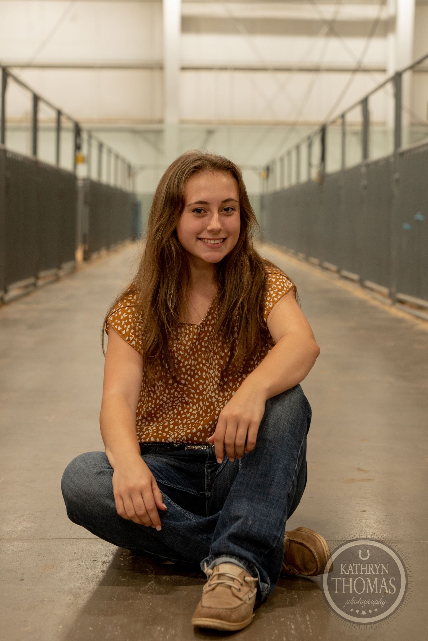 Portrait in a livestock facility hallway wearing a leopard print top and blue jeans.