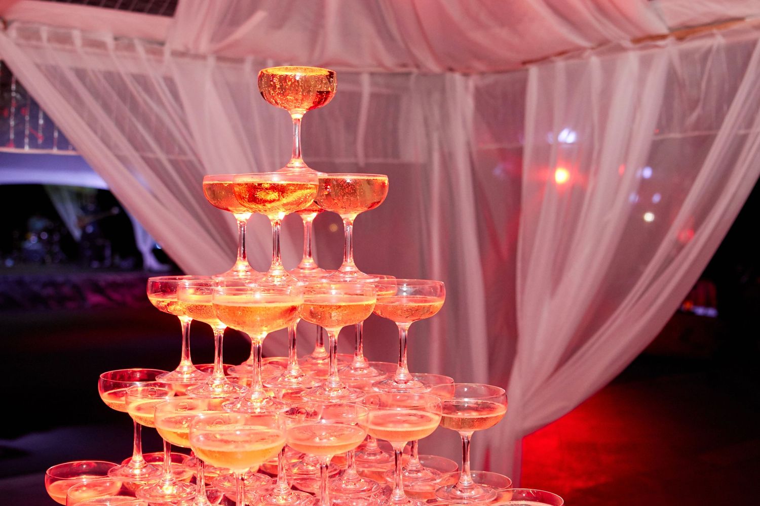 Elegant champagne tower with glowing orange lighting creating a dramatic party atmosphere.