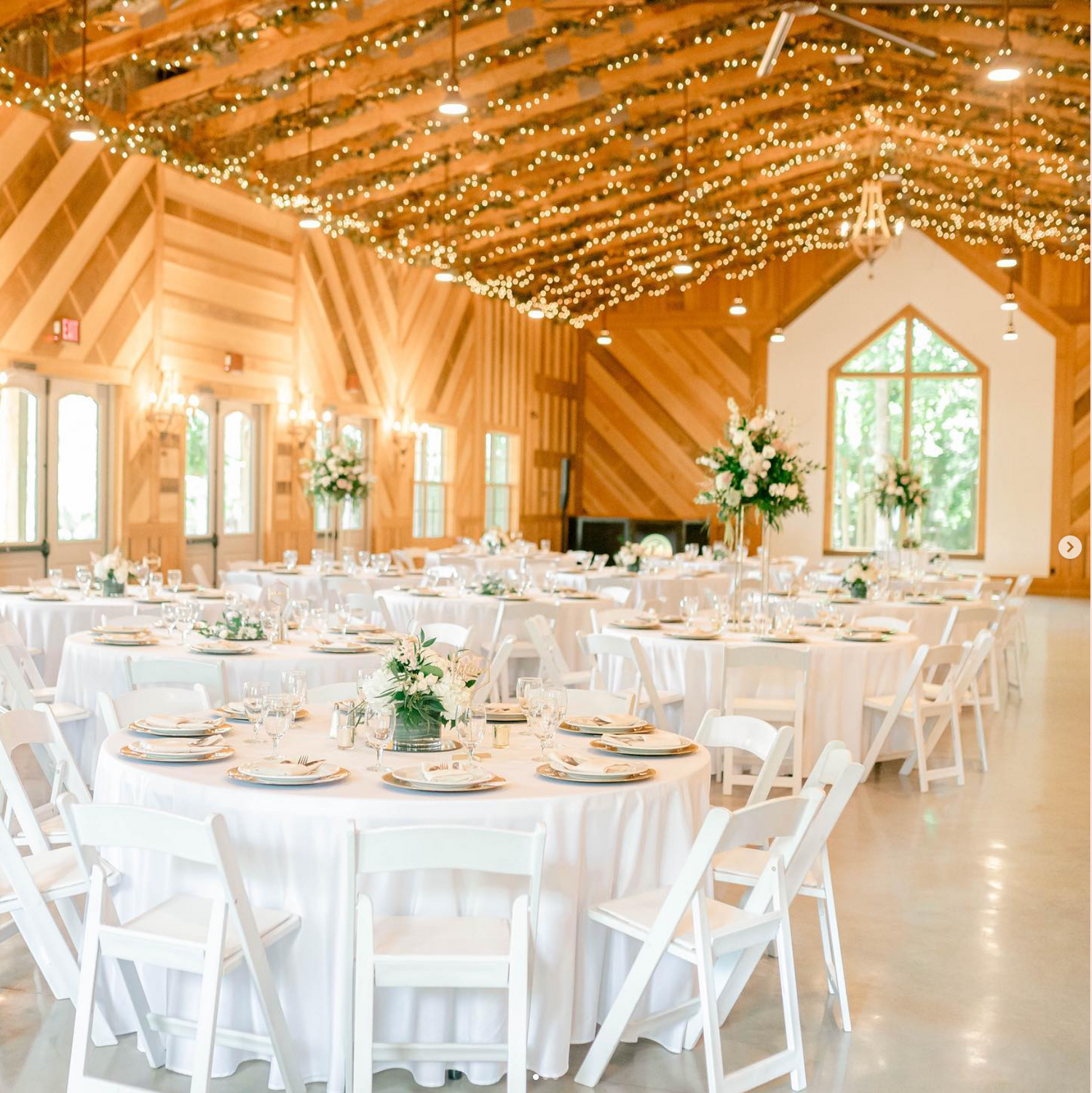 An elegant wedding reception venue with twinkling lights and white table settings.