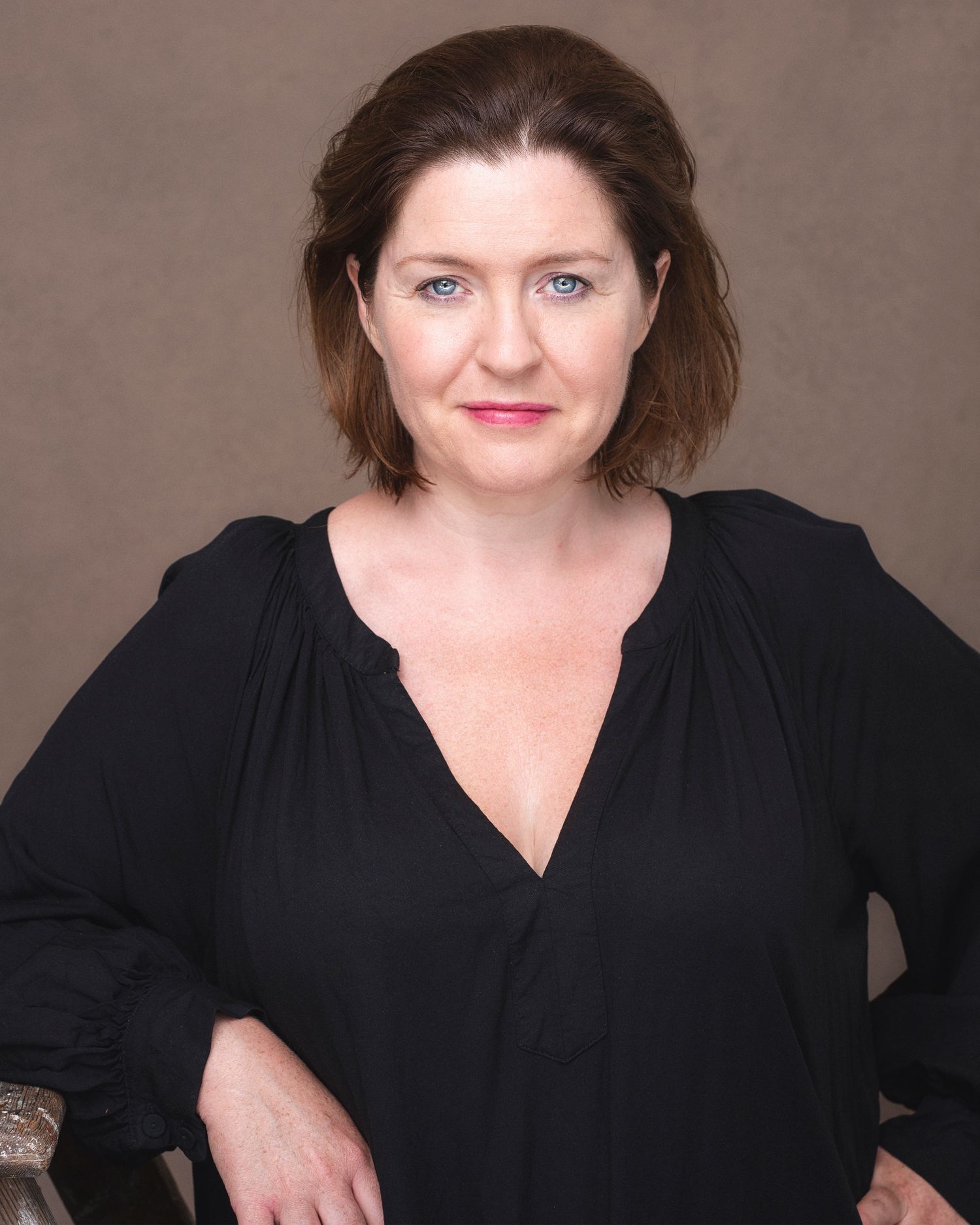 Professional portrait of a woman with short brown hair wearing a black v-neck blouse.