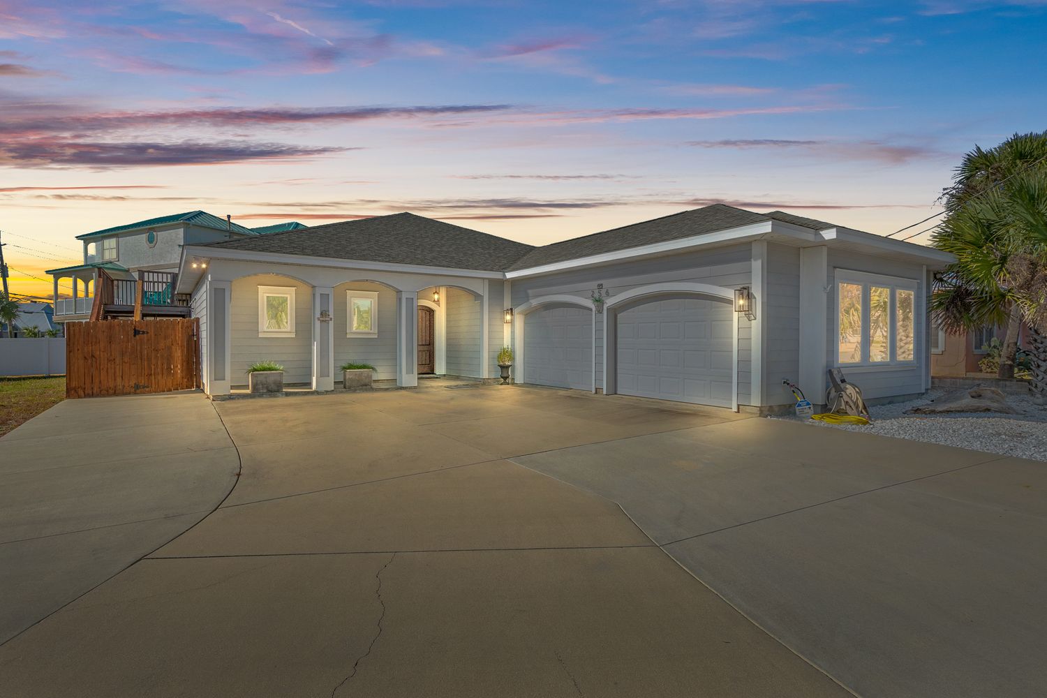 Modern gray house with three-car garage illuminated at twilight.