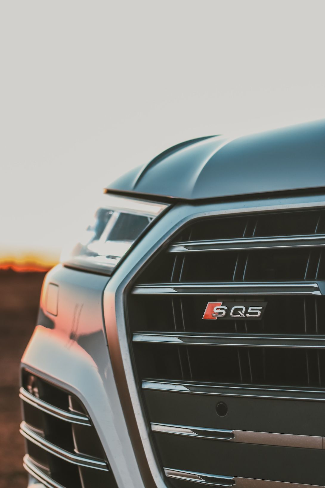 Close-up of an Audi SQ5 front grille with signature badging captured during sunset.