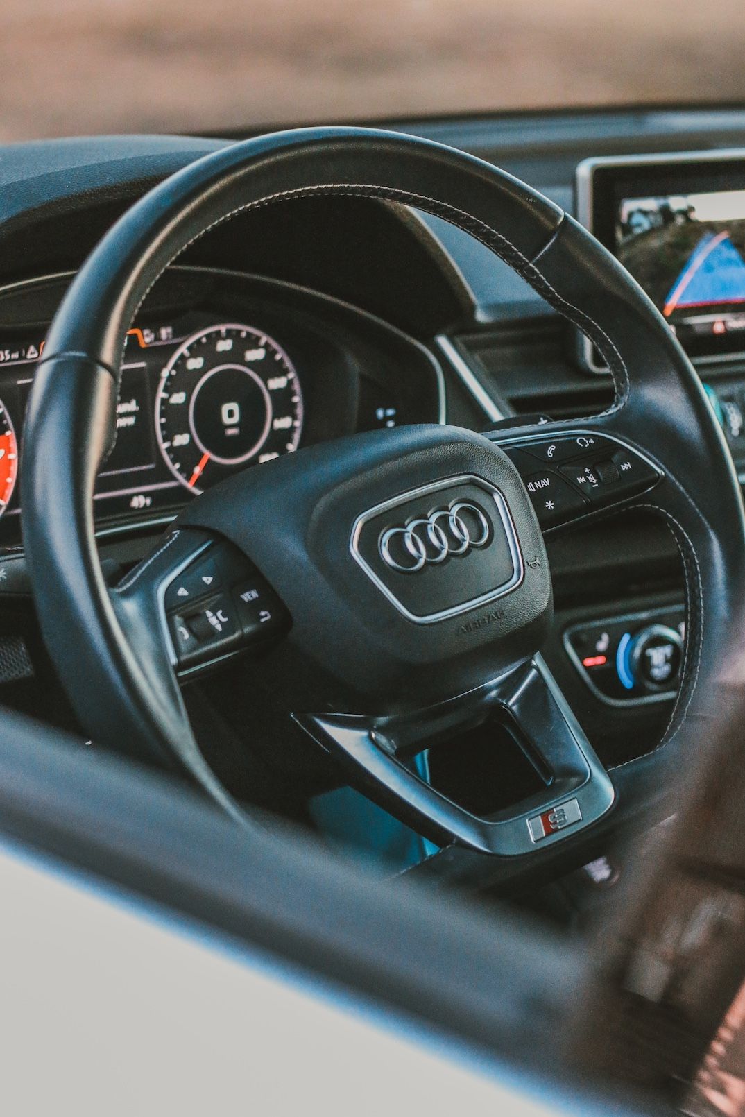 Interior view of an Audi steering wheel and digital dashboard display in a modern luxury vehicle.
