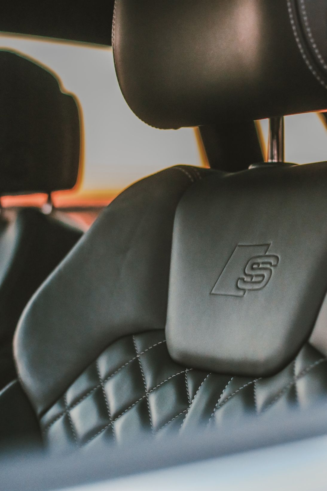 Close-up of luxurious quilted leather car seat with S-line emblem.