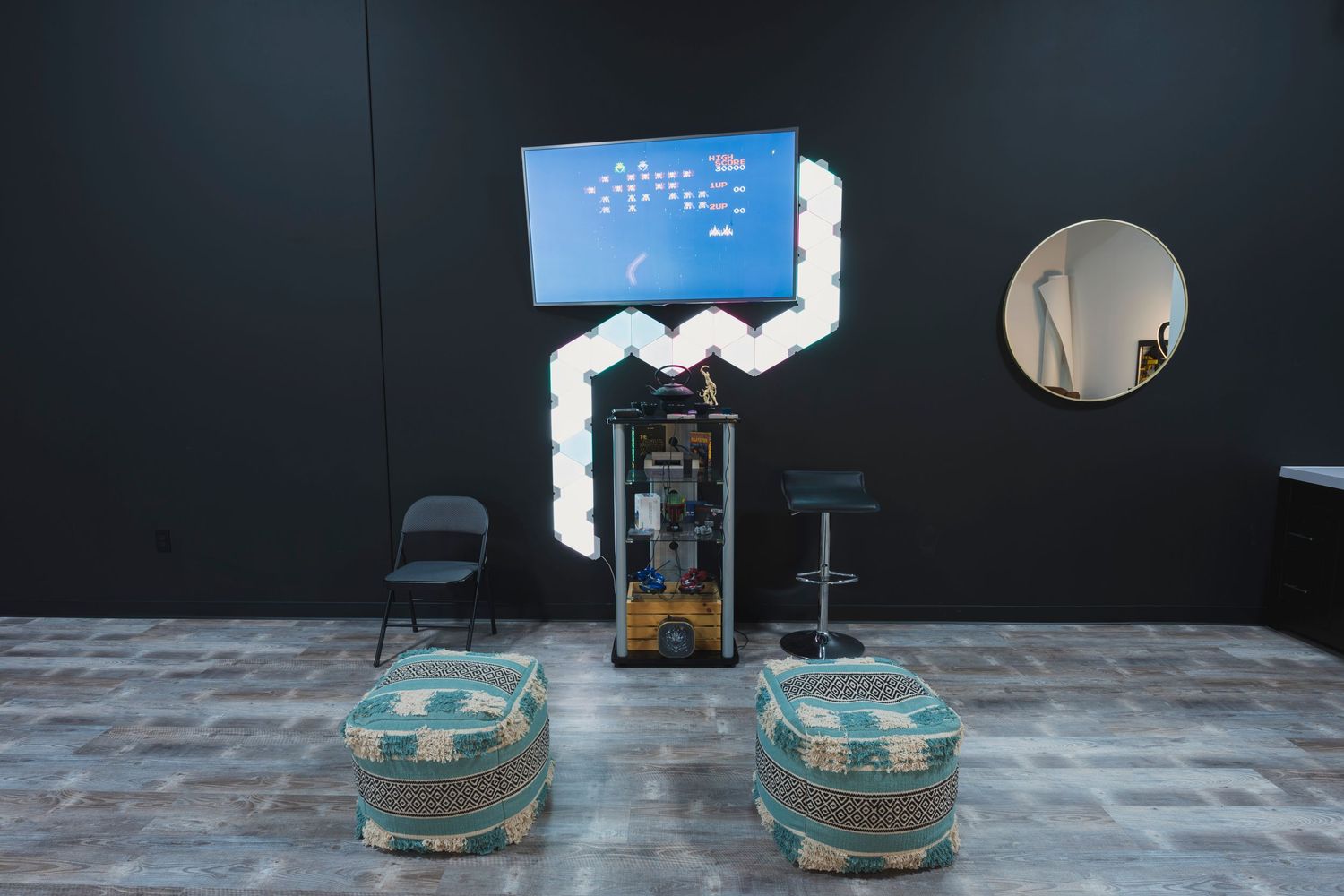 Studio setup with decorative glass containers and digital display mounted on dark wall.