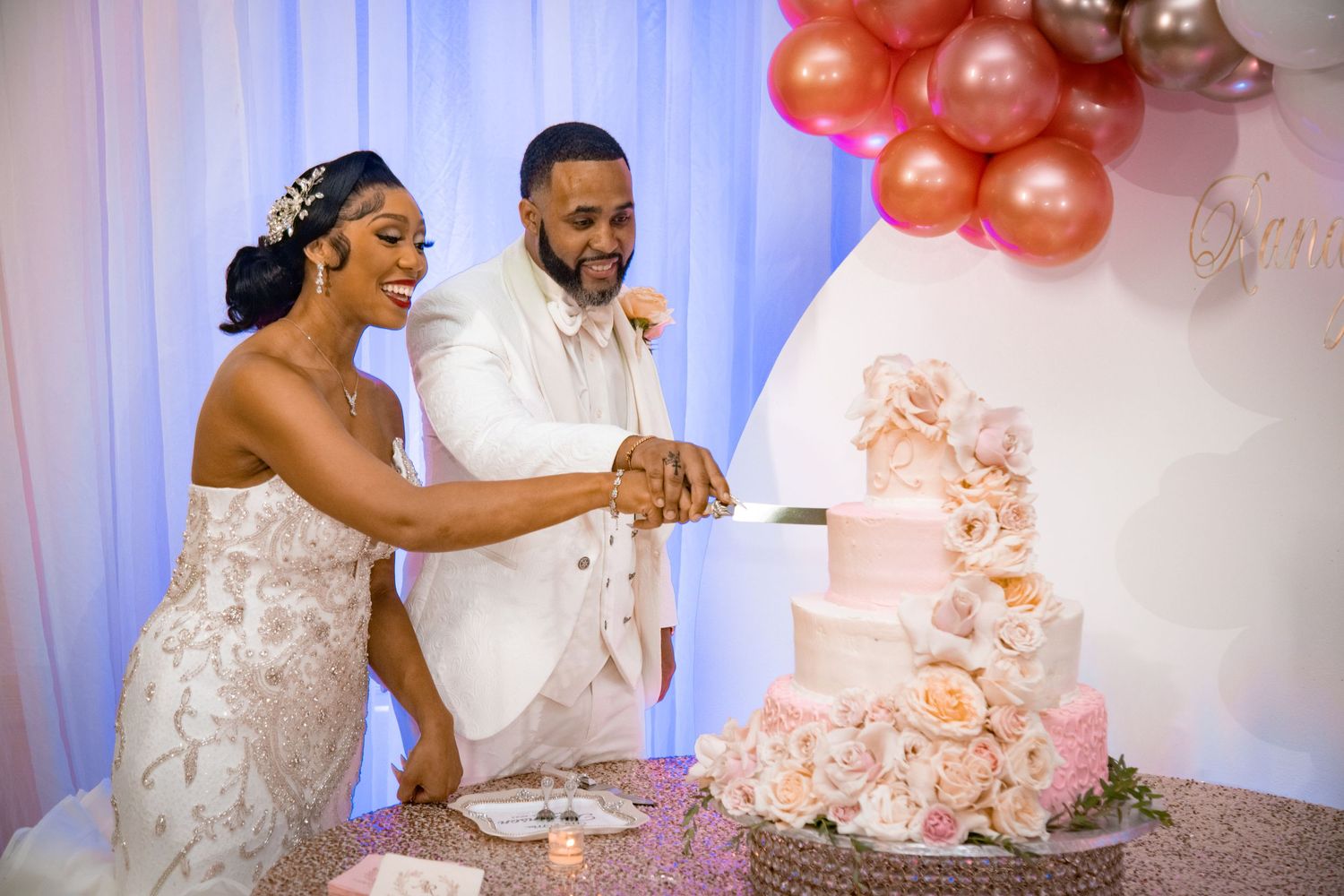 Couple cutting their elegant pink and white wedding cake at reception.