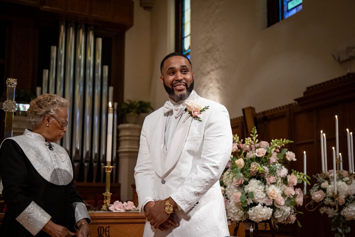 Wedding ceremony in church sanctuary with elegant floral decorations and organ pipes.