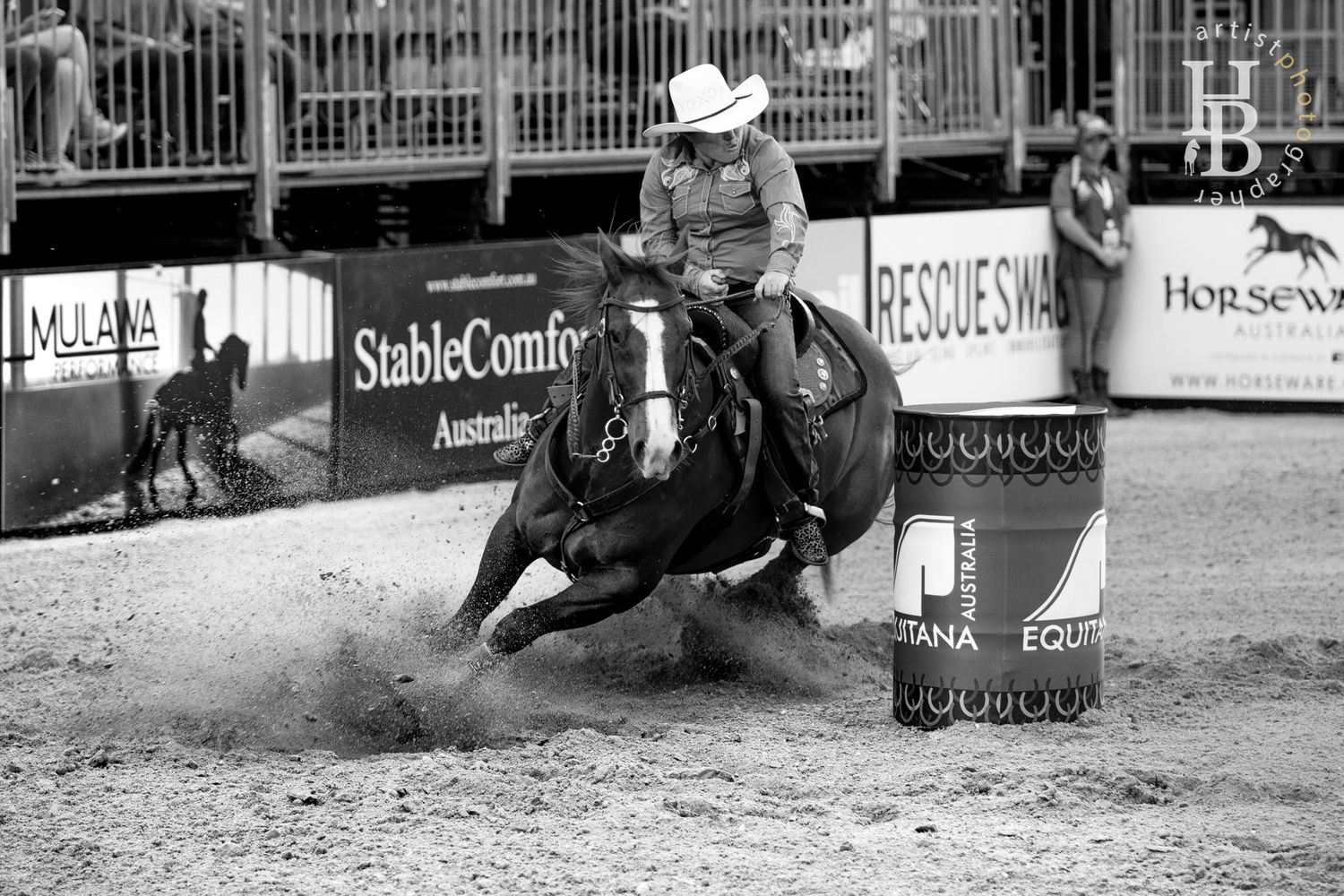 Barrel racing cowboy kicks up dust while making a sharp turn at a rodeo competition.