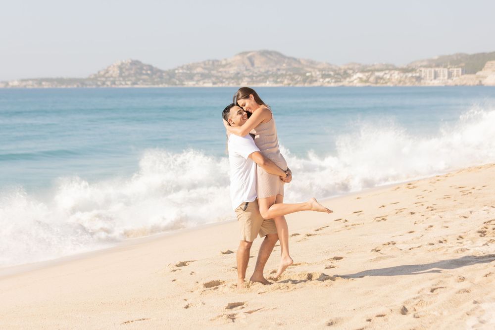 Scenic beach photoshoot with waves crashing and mountains in the background.