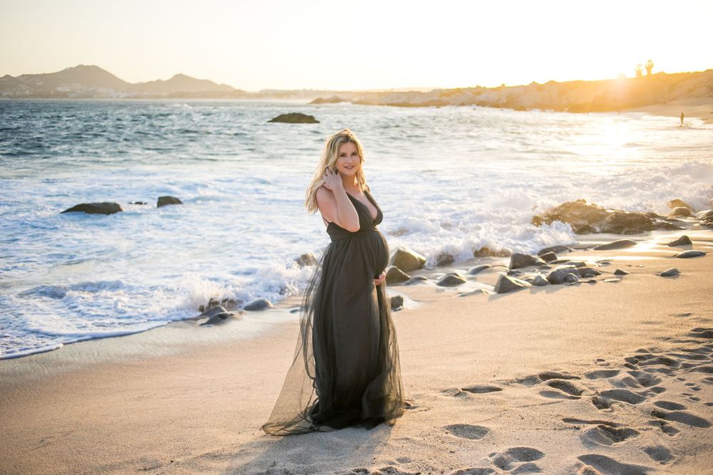 Scenic beach photography session with mountains and ocean waves at golden hour.