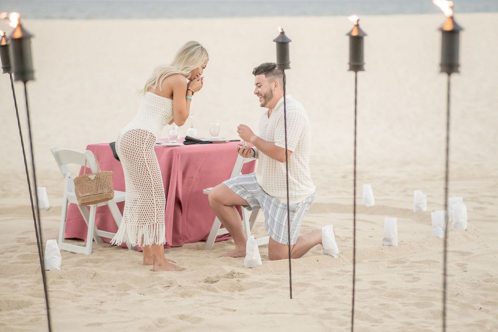 Romantic beach photoshoot at sunset with soft lighting and sandy backdrop.