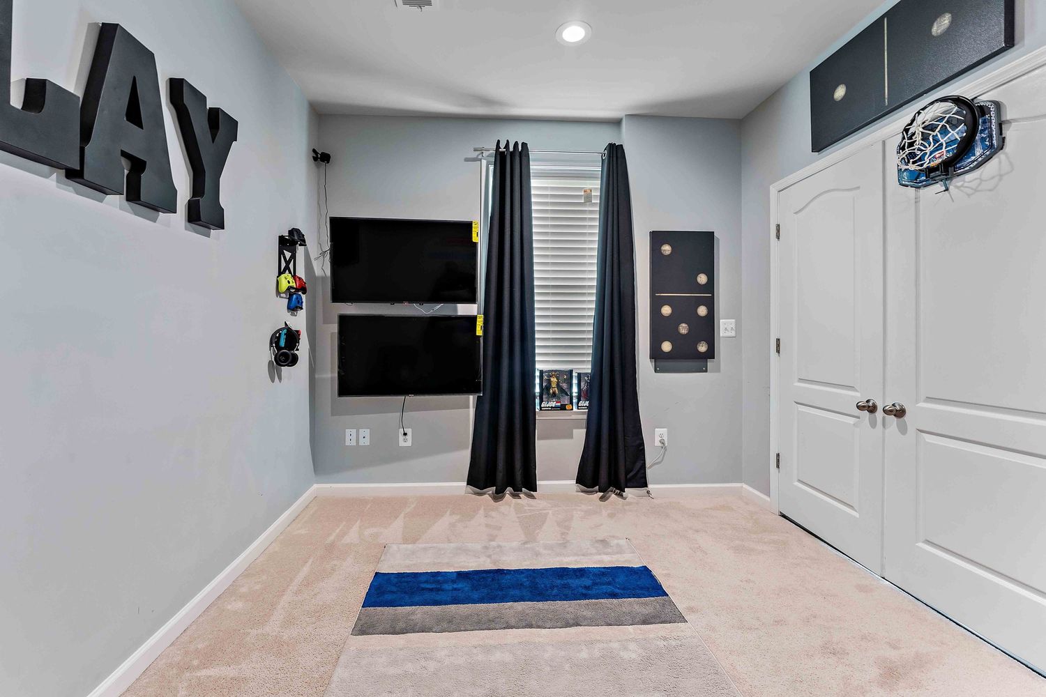 Modern game room with gray walls, black curtains, and sports decor featuring 'JAY' text art.